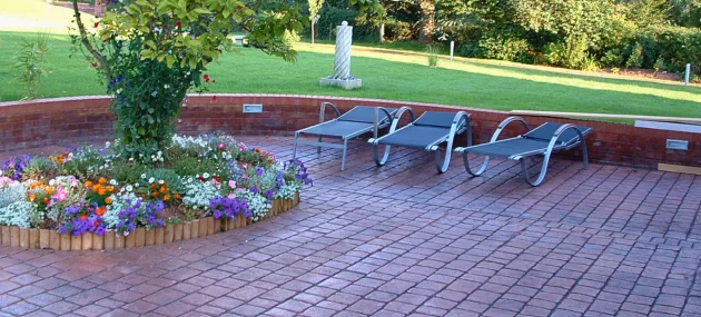 Pattern imprinted concrete patio with flower bed and sun loungers by PICS supplies.