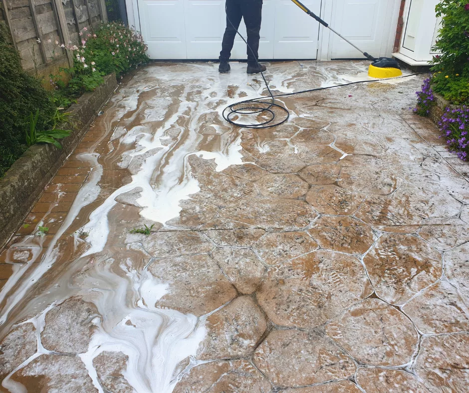 PICS pattern imprinted concrete driveway being cleaned with a pressure washer.