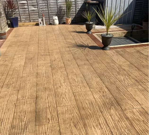 Pattern imprinted concrete patio by PICS, featuring wood texture and plant pots.